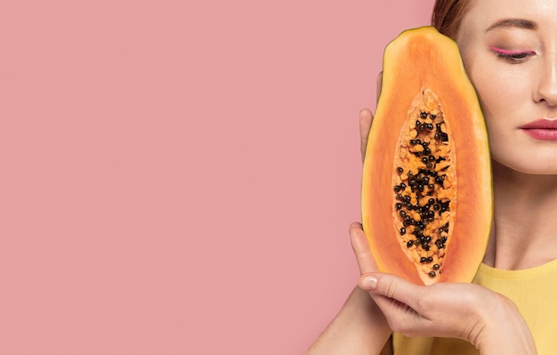 Retrato de mujer hermosa pelirroja sosteniendo una fruta con espacio de copia