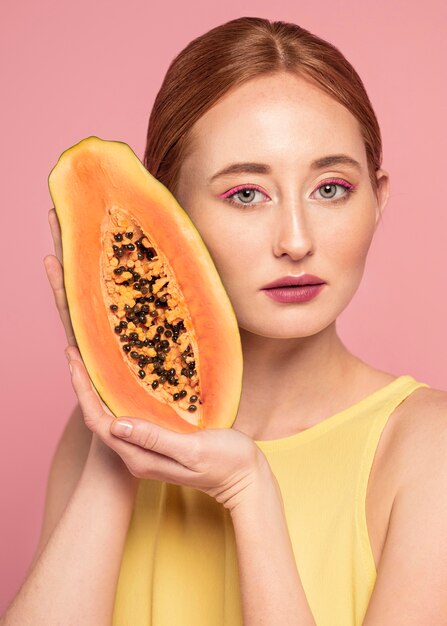 Retrato de mujer hermosa pelirroja sosteniendo una fruta