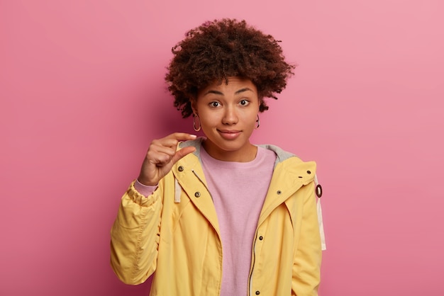 Retrato de mujer hermosa de pelo rizado muestra algo muy pequeño