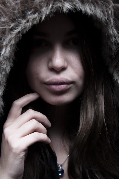 Retrato de mujer hermosa de pie y mirando en la chaqueta negra con capucha peluda