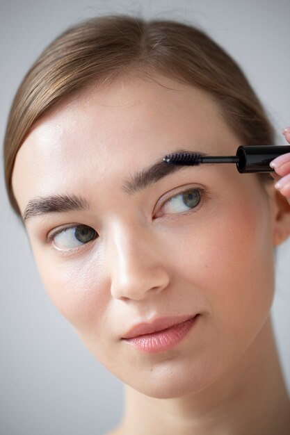 Retrato de mujer hermosa con piel clara cepillándose las cejas