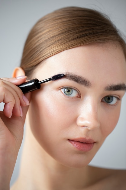 Retrato de mujer hermosa con piel clara cepillándose las cejas