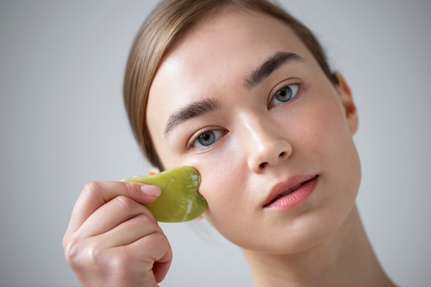 Retrato de mujer hermosa con piel clara con guasha para masajear su rostro