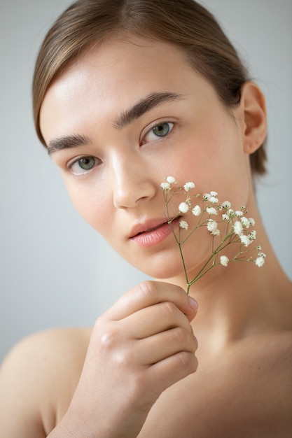 Retrato de mujer hermosa con piel clara posando con flores de aliento de bebé