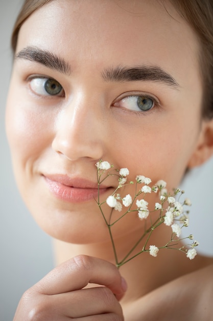 Retrato de mujer hermosa con piel clara posando con flores de aliento de bebé