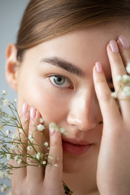 Retrato de mujer hermosa con piel clara posando con flores de aliento de bebé