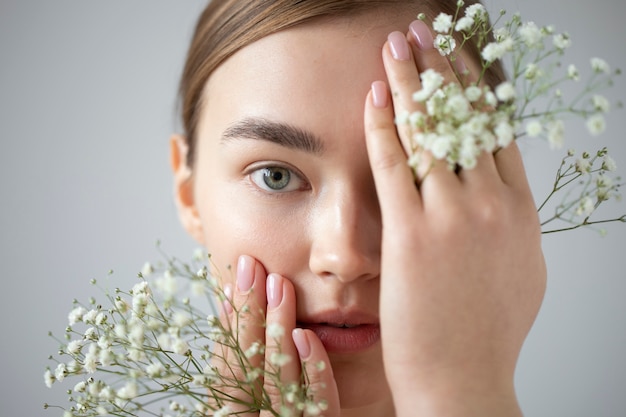 Foto gratuita retrato de mujer hermosa con piel clara posando con flores de aliento de bebé