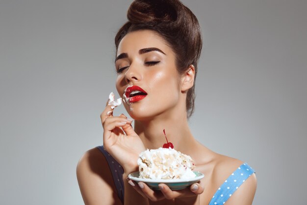 Retrato de mujer hermosa pin-up comiendo pastel