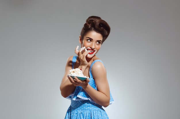 Retrato de mujer hermosa pin-up comiendo pastel