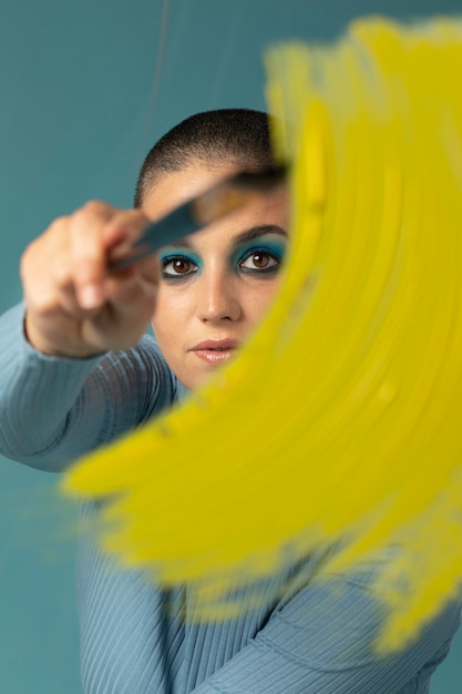 Foto gratuita retrato de mujer hermosa posando en un cuello alto con trazo de pincel de pintura amarilla