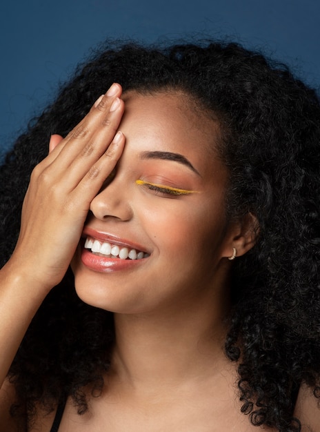 Retrato de una mujer hermosa que cubre su ojo derecho y sonriendo