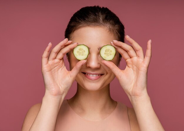 Retrato de mujer hermosa que cubre sus ojos con rodajas de pepino