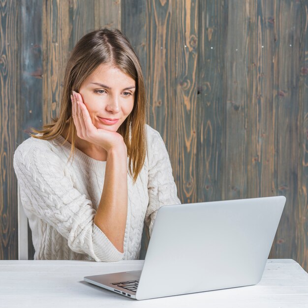 Retrato de una mujer hermosa que usa la computadora portátil sobre el escritorio