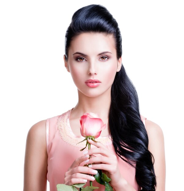 Retrato de mujer hermosa sensual con rosa rosa sobre pared blanca.