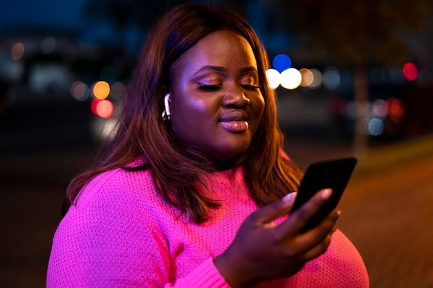 Retrato de mujer hermosa con smartphone por la noche en las luces de la ciudad