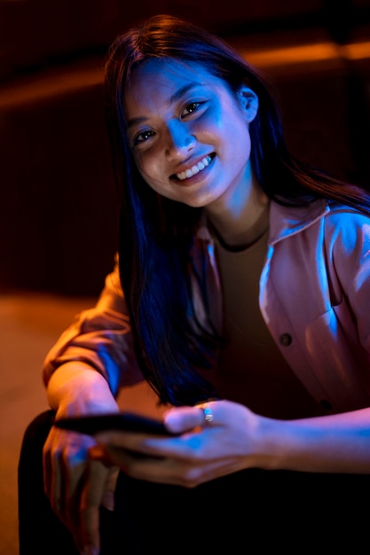 Retrato de mujer hermosa con smartphone por la noche en las luces de la ciudad