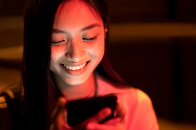 Retrato de mujer hermosa con smartphone por la noche en las luces de la ciudad