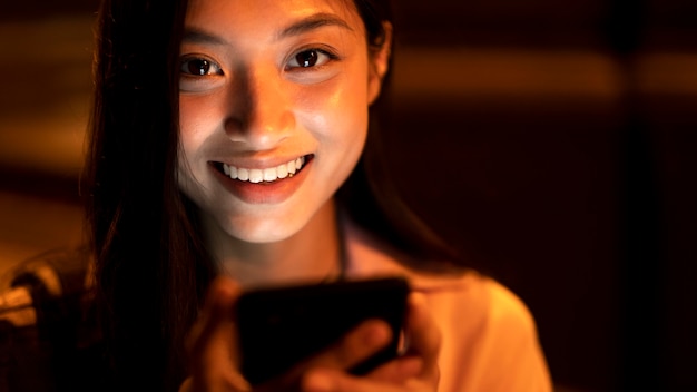 Retrato de mujer hermosa con smartphone por la noche en las luces de la ciudad