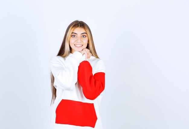 Retrato de una mujer hermosa en sudadera con capucha caliente de pie y mirando a la cámara