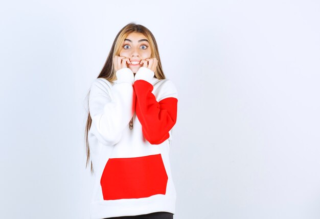 Retrato de una mujer hermosa en sudadera con capucha caliente de pie y mirando a la cámara