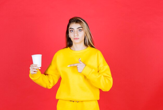Retrato de mujer hermosa en traje amarillo posando con taza de té
