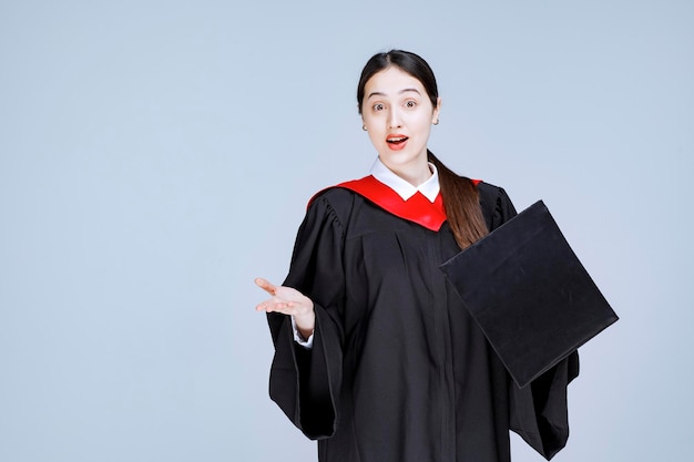 Retrato de mujer hermosa en traje de graduación de pie sobre la pared. Foto de alta calidad