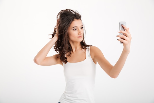 Retrato de una mujer hermosa vestida de tanque-tapa teniendo una autofoto