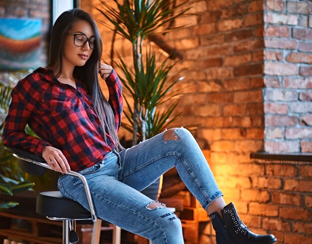 Retrato de una mujer hipster morena vestida con una camisa de lana roja en una habitación con interior de loft.