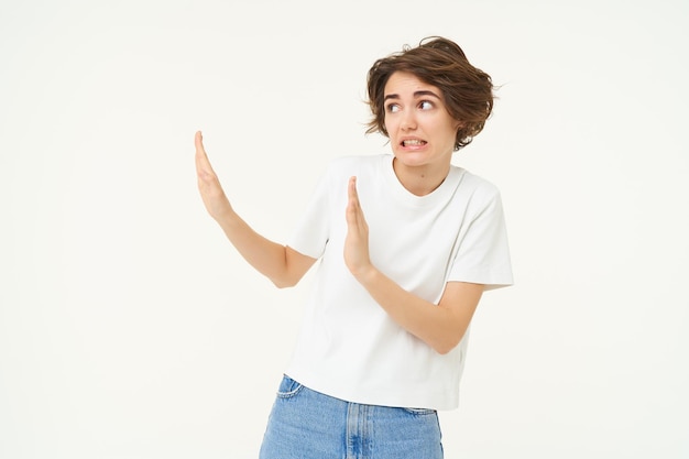 Foto gratuita retrato de una mujer incómoda y disgustada muestra un gesto de bloqueo de mano hacia la izquierda evitando algo