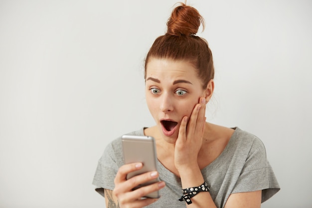 Foto gratuita retrato de mujer independiente joven ansiosa o conmocionada de cerca mirando el teléfono viendo malas noticias