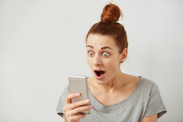 Retrato de mujer independiente joven ansiosa o conmocionada de cerca mirando el teléfono viendo malas noticias