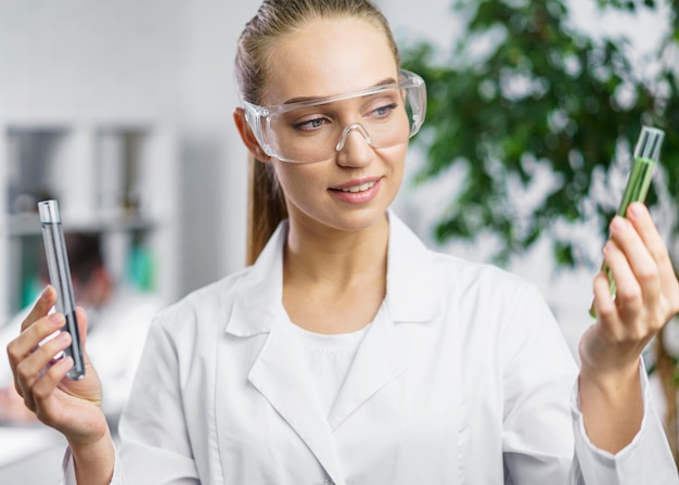 Retrato de mujer investigadora en el laboratorio con tubos de ensayo y gafas de seguridad