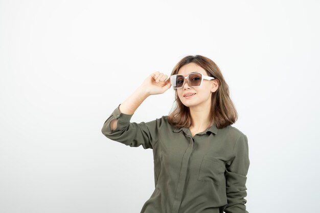 Retrato de mujer joven adorable en anteojos de pie sobre blanco. foto de alta calidad