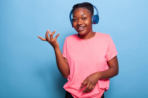 Retrato de mujer joven afroamericana usando audífonos sonriendo a la cámara