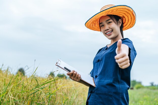 Retrato mujer joven agricultor asiático con sombrero de paja y sosteniendo el portapapeles en la mano
