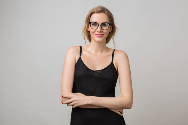 Retrato de mujer joven aislada en blanco con gafas en pose de confianza y vistiendo un vestido negro