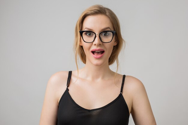 Retrato de mujer joven aislada en blanco con gafas en pose de confianza y vistiendo un vestido negro