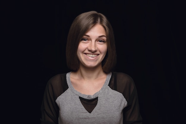 Foto gratuita retrato de mujer joven aislada sobre fondo negro de estudio de cerca. photoshot de emociones reales de modelo femenino. preguntándose, emocionado y asombrado. expresión facial, concepto de emociones humanas.