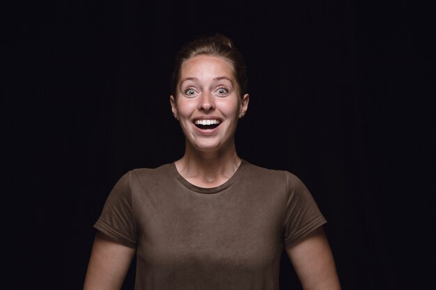 Retrato de mujer joven aislada sobre fondo negro de estudio de cerca. Photoshot de emociones reales de modelo femenino. Preguntándose, emocionado y asombrado. Expresión facial, concepto de emociones humanas.