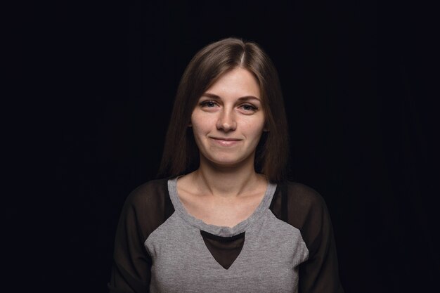 Retrato de mujer joven aislada sobre fondo negro de estudio de cerca. Photoshot de emociones reales de modelo femenino. Sonriendo, sintiéndose feliz. Expresión facial, concepto de emociones humanas puras y claras.