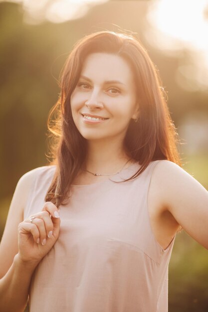 Retrato de mujer joven alegre con cabello oscuro caminando en el jardín