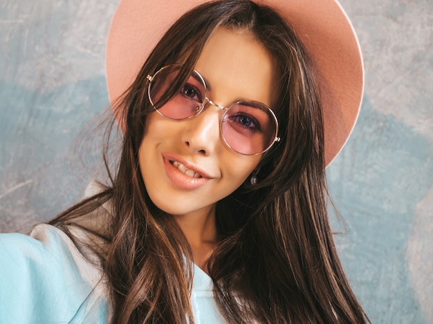 Retrato de mujer joven alegre tomando foto selfie con inspiración y vistiendo ropa moderna y sombrero.