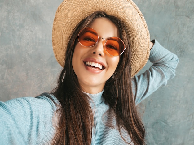 Retrato de mujer joven alegre tomando foto selfie y vistiendo ropa moderna y sombrero.