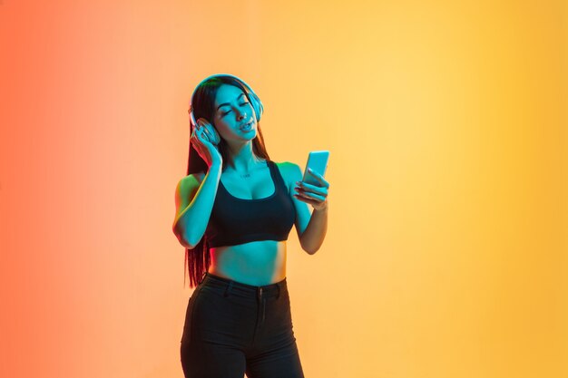 Retrato de mujer joven en amarillo-naranja en luz de neón