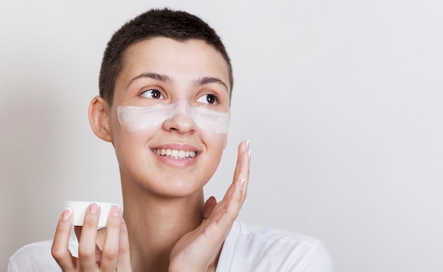 Retrato mujer joven aplicar crema en la cara