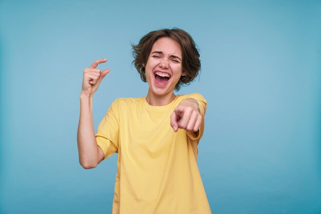 Retrato de una mujer joven apuntando a algo y riendo