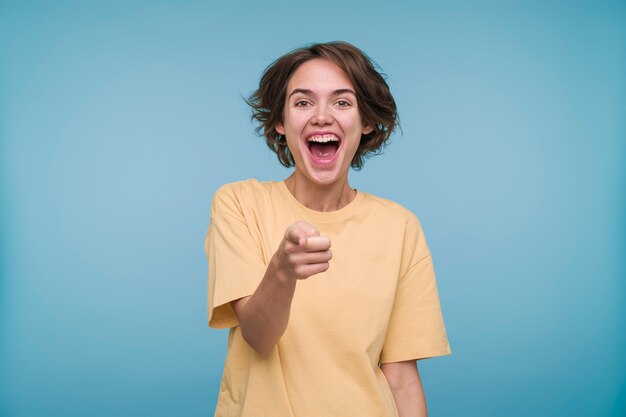 Retrato de una mujer joven apuntando a algo y riendo