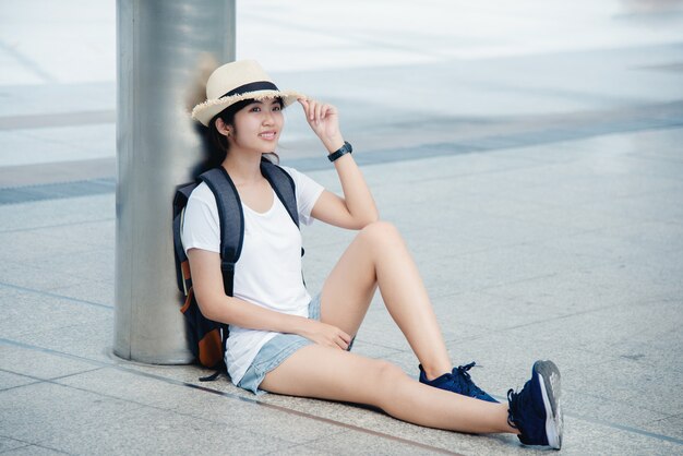 Retrato de una mujer joven asiática feliz que se sienta en la ciudad