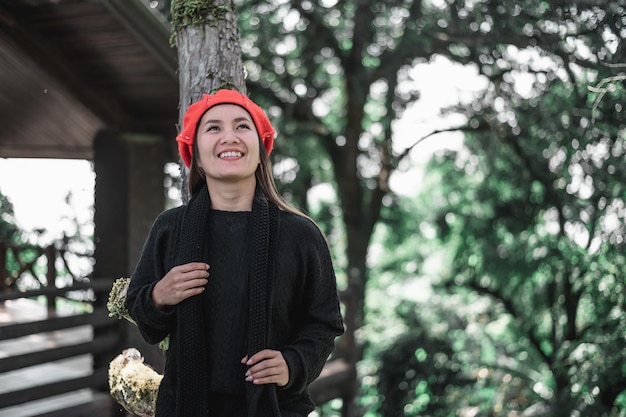 Foto gratuita retrato de mujer joven asiática feliz en traje de invierno en el bosque con espacio de copia concepto de vacaciones y viajes