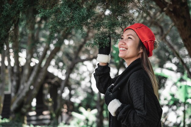 Retrato de mujer joven asiática feliz en traje de invierno en el bosque con espacio de copia Concepto de vacaciones y viajes